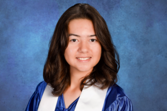 A high school graduate looking directly at the camera with a bright, welcoming, and genuine smile. They wear a satin blue graduation gown and white stole against a clean, well-lit background.